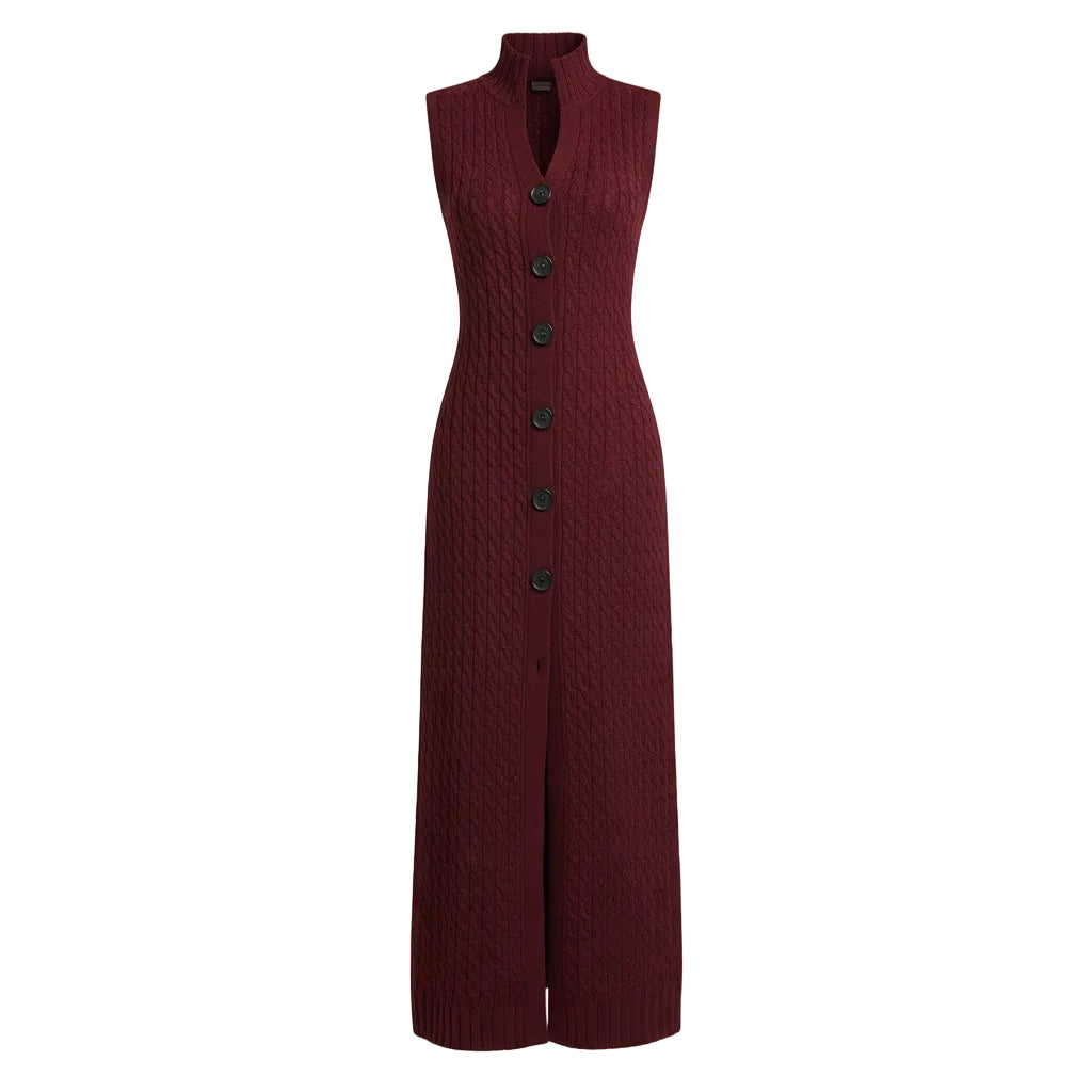 A woman models a long burgundy cable-knit sleeveless cardigan with black buttons, worn over white wide-leg pants and styled with a woven tan handbag against a textured gray studio background.