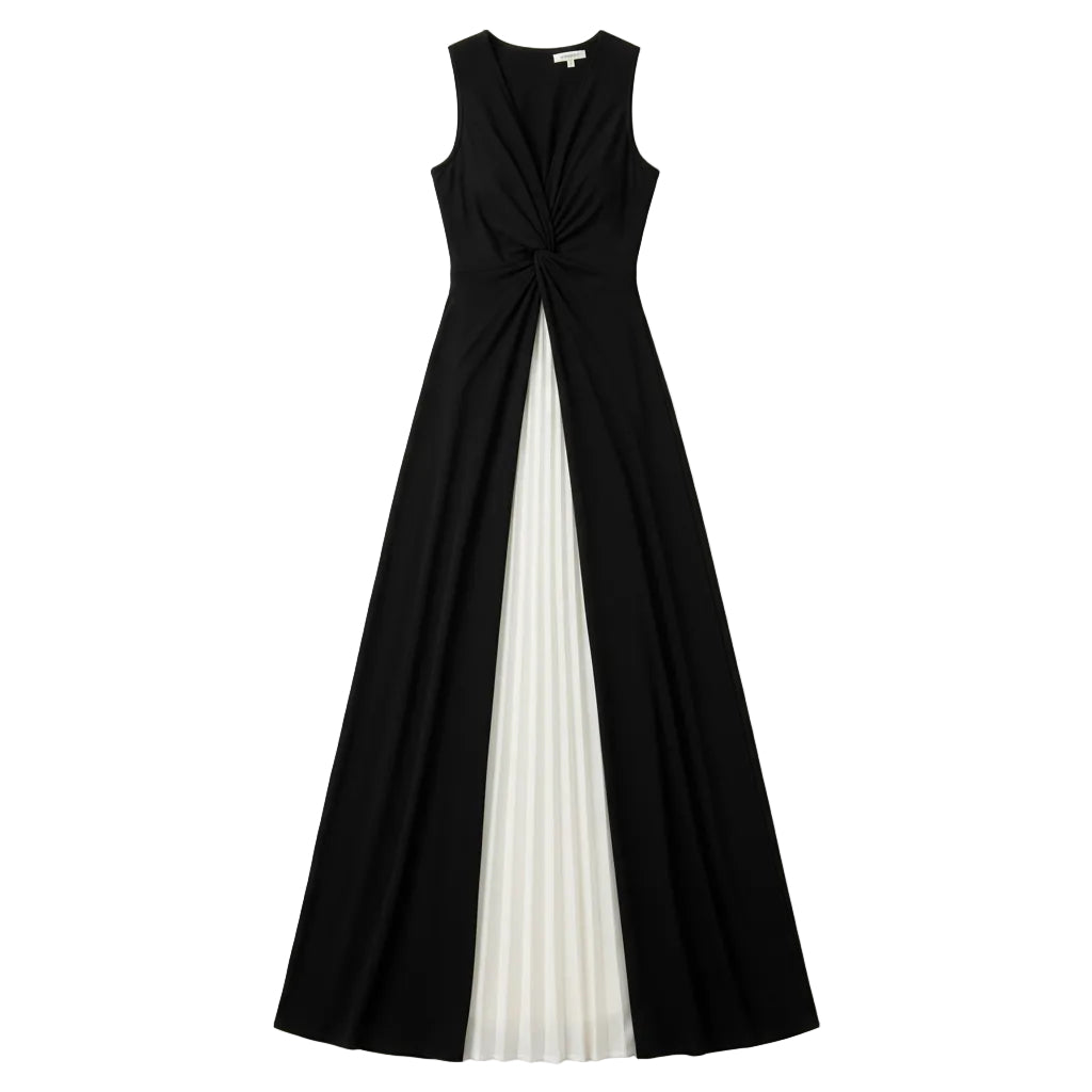 A woman models a sleeveless, floor-length maxi dress with a black and white color-blocked design, standing against a modern gray tiled wall.