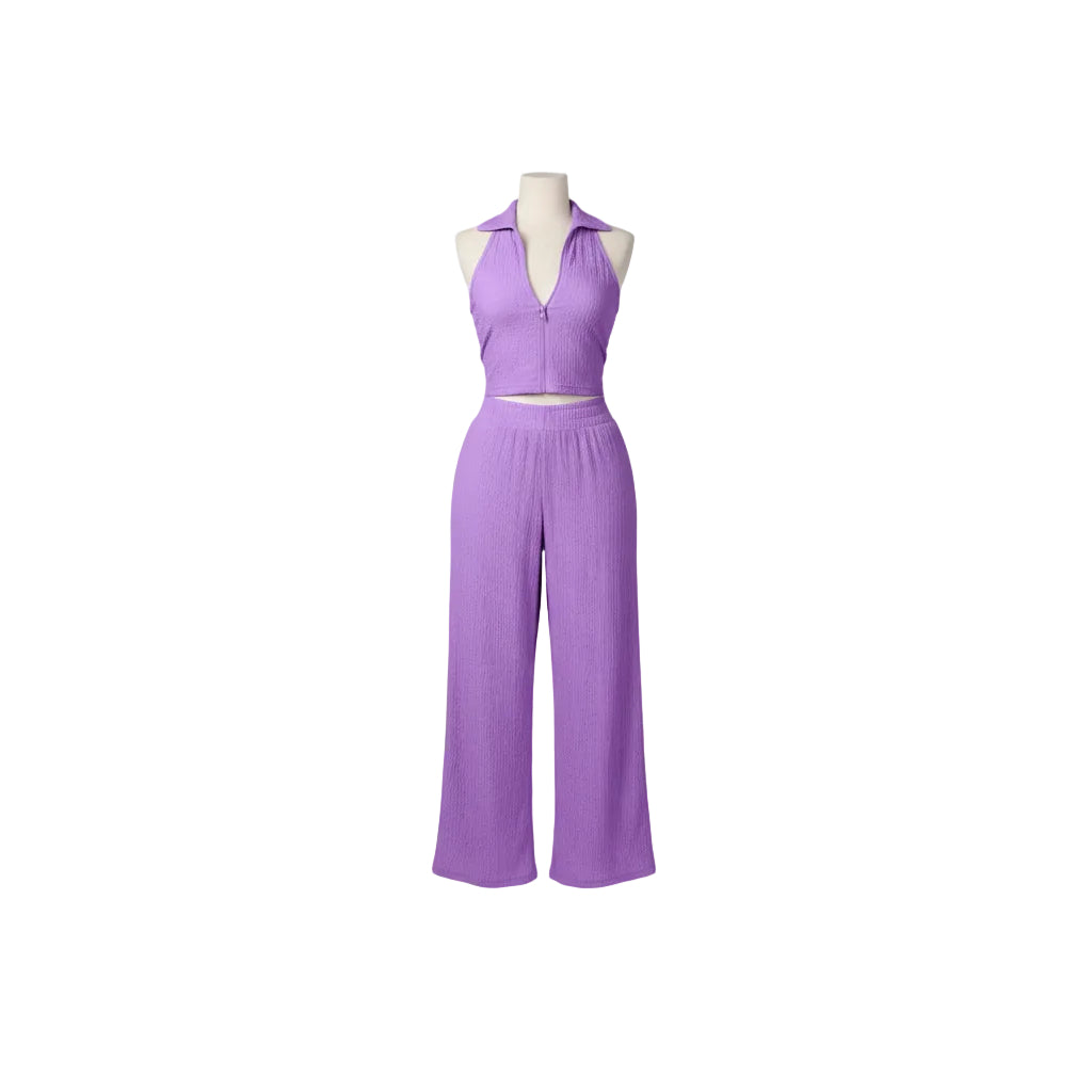 Woman in a purple jumpsuit standing in a doorway.